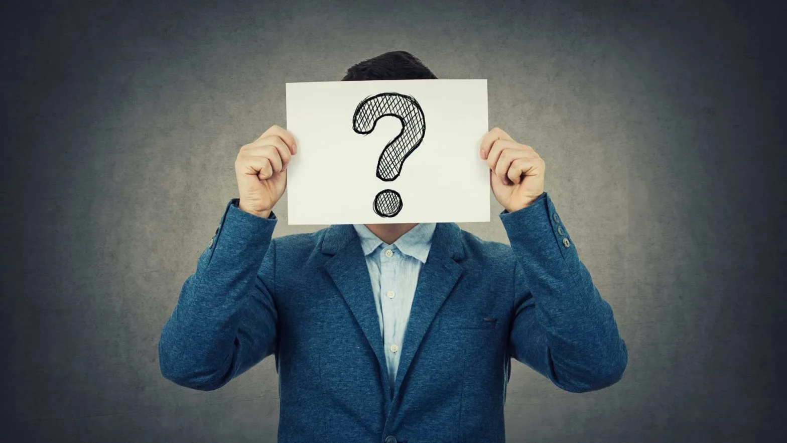 Person in a blue suit holding a sheet of paper with a large question mark covering their face, symbolizing identity verification, uncertainty, and background checks.