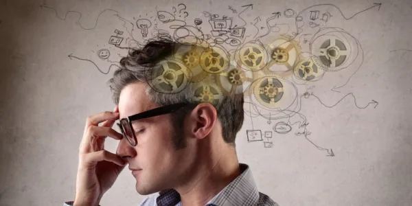 Person in glasses deep in thought with illustrated gears and cognitive processes emerging from their head, symbolizing how intelligent decision-making and mental shortcuts can still be exploited by deception and sophisticated scams