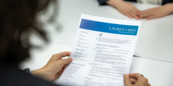 Recruiter reviewing a candidate's resume during a job interview, highlighting employment history, qualifications, and professional experience for hiring evaluation.